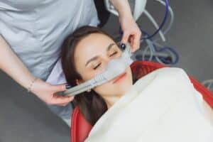 Dental assistant administering dental sedation to a patient to help prevent dental anxiety.